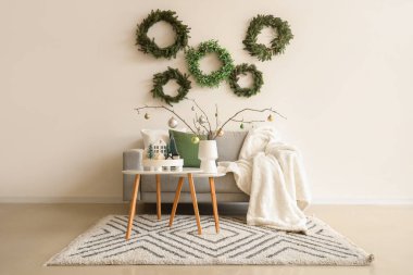 Oturma odasının içinde Noel çelenkleri, kanepe ve masalar var.