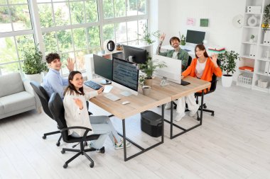 Programcılardan oluşan bir ekip masada el sallıyor.