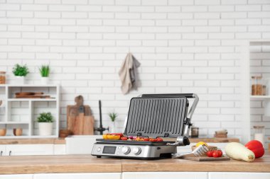 Mutfaktaki ahşap masada sebzeli modern elektrikli ızgara.