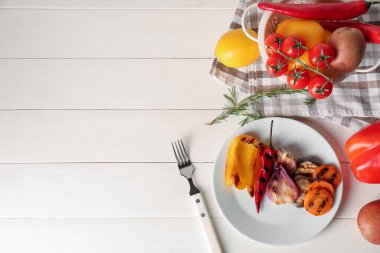 Lezzetli ızgara sebzeli tabak, beyaz ahşap arka planda biberiye ve limon.