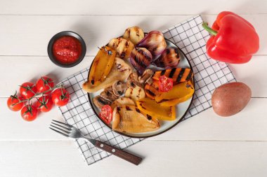 Lezzetli ızgara sebzeli tabak ve ahşap arka planda bir kase sos.