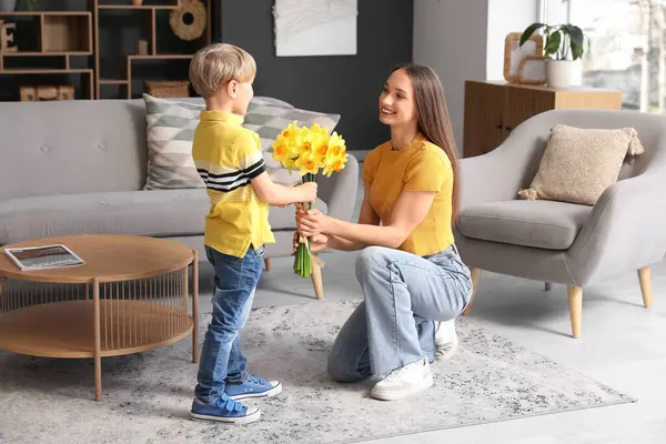 Son greeting his happy mother with bouquet of beautiful narcissus at home