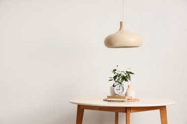 Masada kitaplar ve ışık duvarının yanında kolye bulunan çalar saat