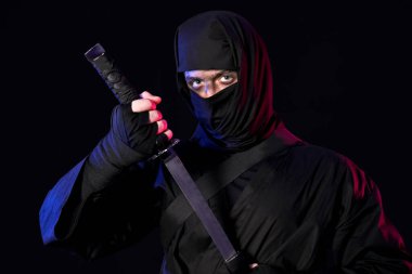 Siyah arka planda kılıç taşıyan erkek ninja.