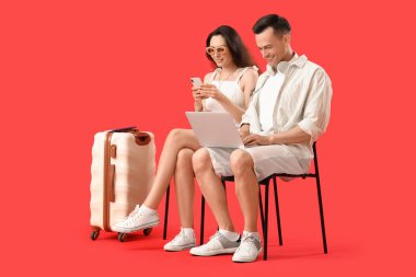 Kırmızı arka planda oturan aletleri olan genç çift.