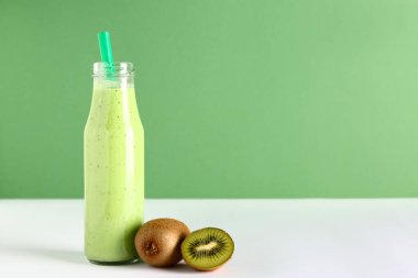 Beyaz masada bir şişe taze kivi püresi.