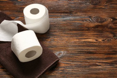 Tahta arka planda tuvalet kağıdı ve havlu ruloları.