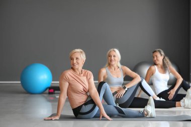 Sportif olgun kadınlar spor salonunda yoga yapıyor.