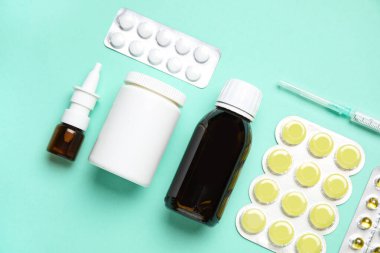 Farklı haplar, şırınga ve mavi arka planda ilaç şişeleri.