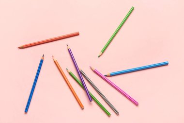 Pembe arka planda renkli kalemler grubu