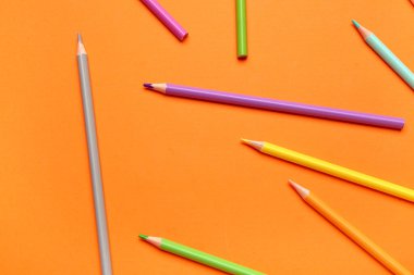 Turuncu arka planda renkli kalemler grubu