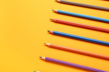 Sarı arkaplanda renkli kalemler grubu