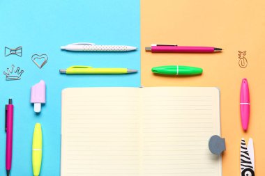 Renkli arkaplanda farklı kırtasiye malzemesi olan defter