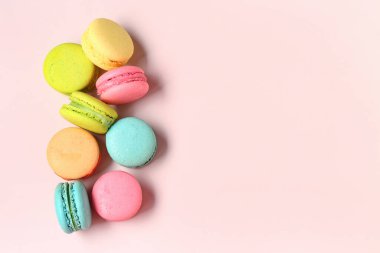 Pembe arka planda farklı tatlı badem kurabiyeleri.