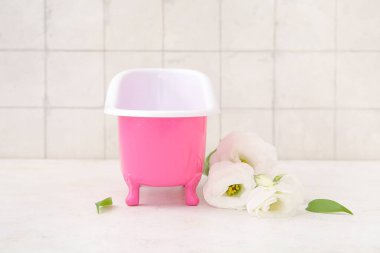 Küçük küvet ve güzel Eustoma çiçekleri ışık masasında.