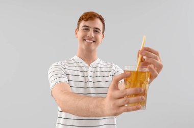 Arka planda bir bardak meyve suyu olan genç bir adam.