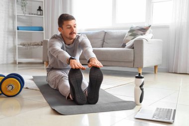 Evde esneme hareketleri yapan genç bir adam. Çevrimiçi eğitim kavramı