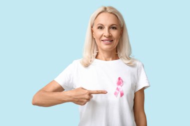 Mavi arka planda pembe kurdeleli olgun bir kadın. Göğüs kanseri farkındalığı konsepti