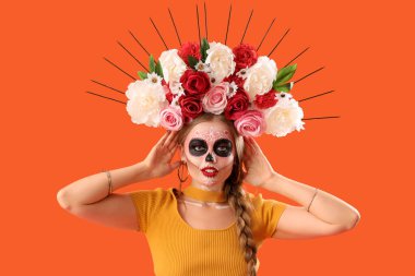 Turuncu arka planda yüzü boyalı genç bir kadın. Meksika Ölüler Günü 'nün Kutlaması (El Dia de Muertos)