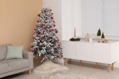 Güzel dekore edilmiş Noel ağacı, kanepe ve şifoniyerle dolu bir oturma odası.