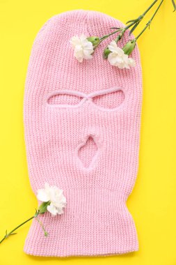 Sarı arka planda karanfil çiçekleri olan pembe kar maskesi.