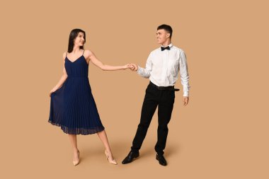 Kahverengi arka planda dans eden güzel genç çift