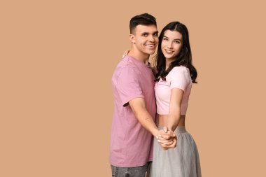 Kahverengi arka planda dans eden mutlu genç çift