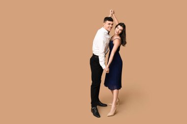 Kahverengi arka planda dans eden mutlu genç çift