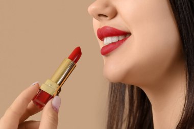 Kırmızı dudaklı ve kahverengi arkaplanda ruj izi olan genç bir kadın, yakın plan.