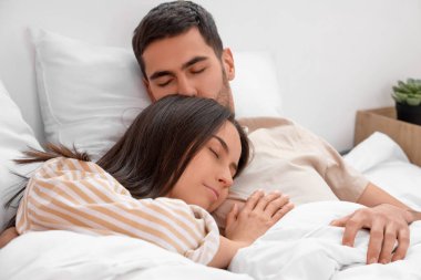 Yatakta uyuyan sevimli genç çift.