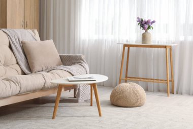 Oturma odasındaki ışık perdesinin yanındaki masada leylak çiçekli vazo.