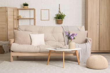 Oturma odasının içinde vazoda leylak çiçekleri ve sehpanın üstünde dergi var.