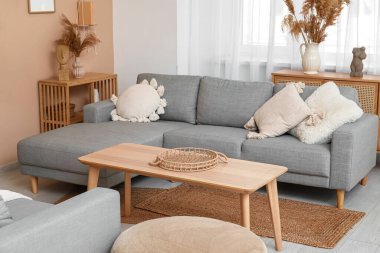 Gri kanepesi, ahşap masası ve otları olan şık bir oturma odası.