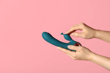 Pembe arka planda vibratörlü kadın elleri