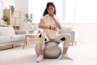 Sportif Afro-Amerikalı kadın evde antrenman yaptıktan sonra nabzını kontrol ediyor.