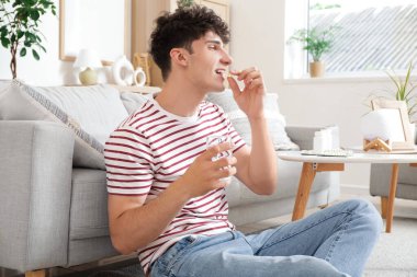 Genç adam evde balık yağı alıyor.