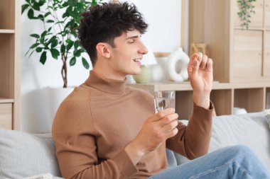 Genç adam evde balık yağı alıyor.