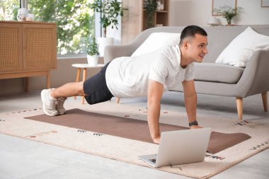 Evde dizüstü bilgisayar eğitimi alan genç bir sporcu.