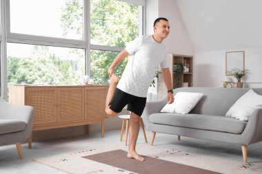 Evdeki paspasın üzerinde spor yapan genç adam.