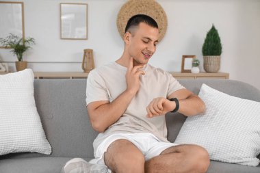 Akıllı genç adam evdeki kanepede nabzını kontrol ediyor.