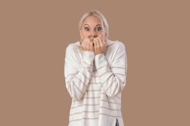 Olgun kadın bej arka planda panik atak geçiriyor.