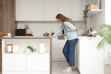 Genç bir kadın mutfakta panik atak geçiriyor.