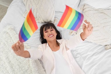 Yatak odasında yatağında LGBT bayrakları olan güzel genç bir kadın.