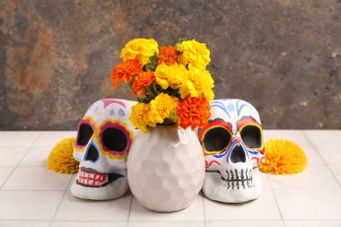 İçinde güzel kadife çiçekleri olan bir vazo ve açık fayanslı masaya insan kafatasları çizdim. El Dia de Muertos