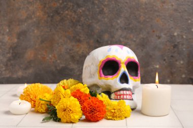 Boyalı insan kafatası, kadife çiçekleri ve yanan mumlar. El Dia de Muertos
