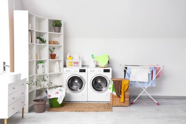 Çamaşır makinesi, çamaşır sepeti ve kurutuculu hafif banyonun içi.