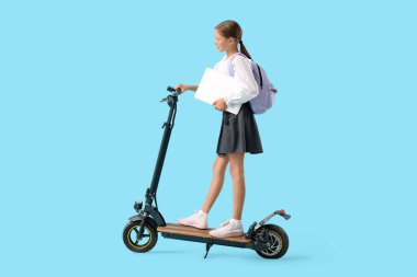 Mavi arka planda elektrikli scooter kullanan, dizüstü bilgisayarı olan tatlı bir kız öğrenci.