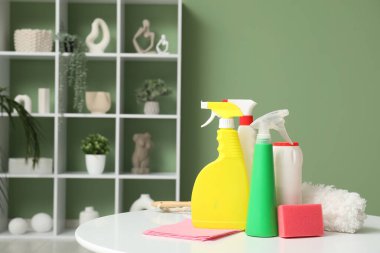 Evdeki masada deterjan, sünger, bez ve pp-tozluk şişeler, yakın plan.