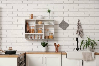 Mutfaktaki raflarda farklı ürünler ve baharatlar olan cam kavanozlar.