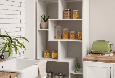 Mutfaktaki raflarda farklı ürünler olan cam kavanozlar.